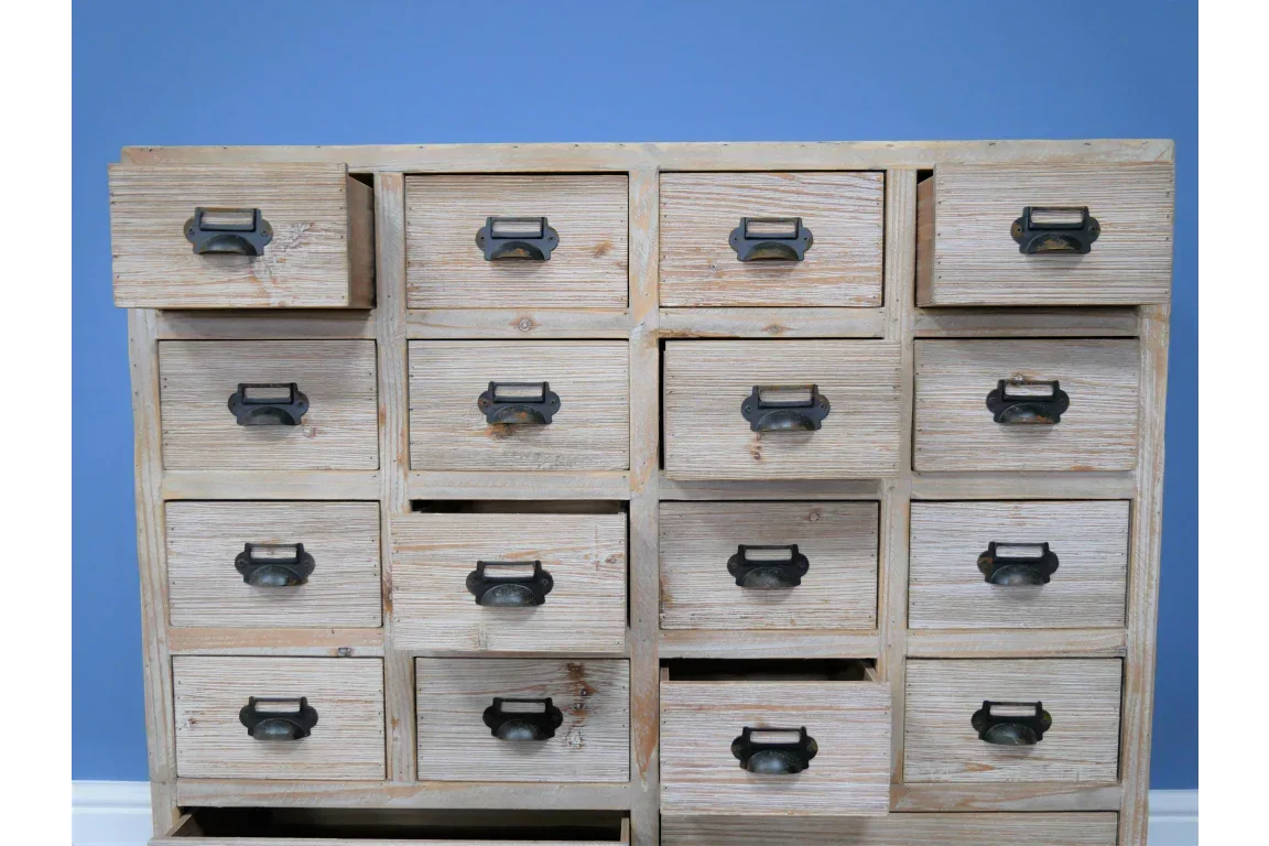 Rustic wooden chest of drawers with metal handles against a blue wall