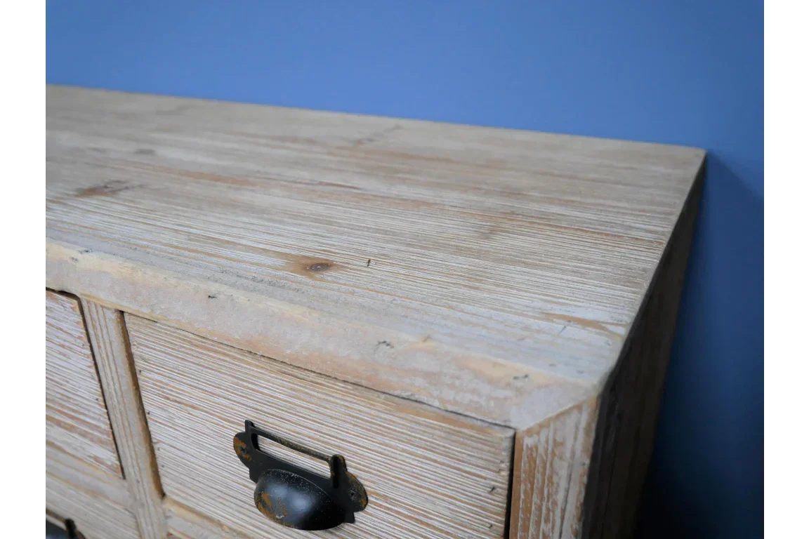 Close view of rustic wooden chest of drawers with metal handle and light wood grain finish