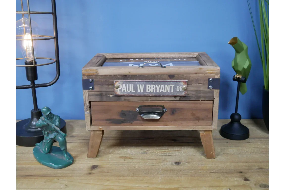 Rustic wooden storage box with metal handle and glass lid on tabletop, decorative accents beside