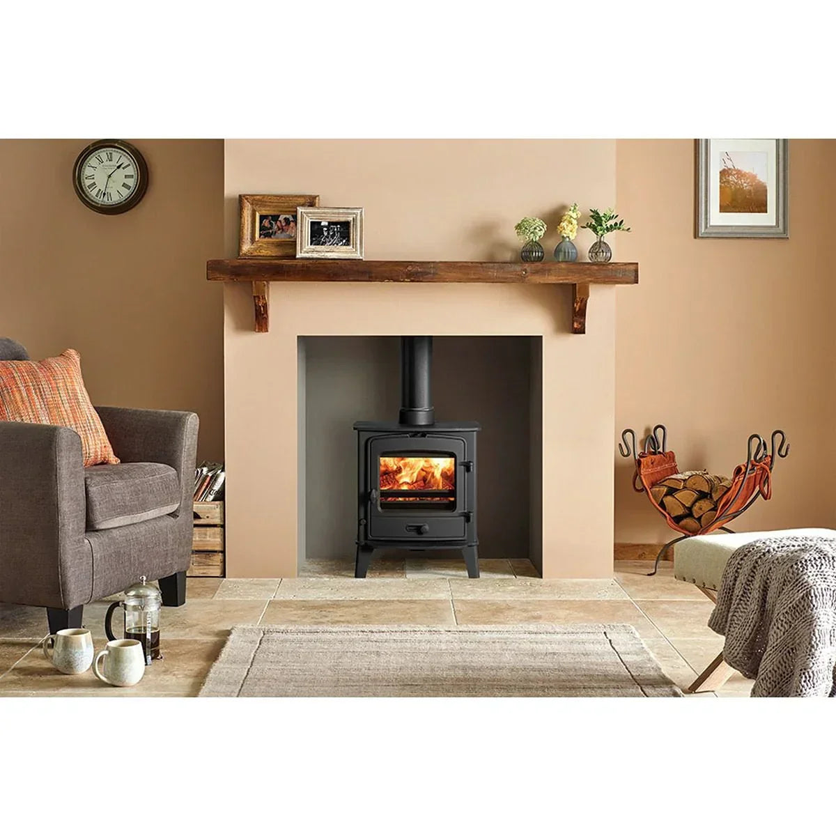 Black wood burning stove with fire in modern living room alcove, logs stored beside hearth