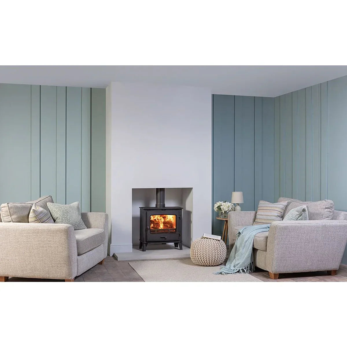Beige fabric sofas in modern living room with log burner and light blue paneled walls