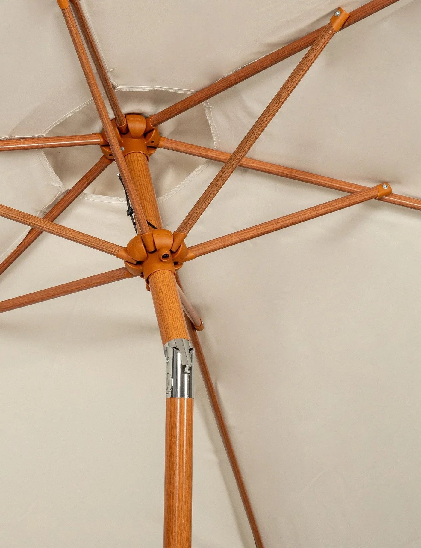 Close-up of wooden parasol frame with beige outdoor fabric canopy