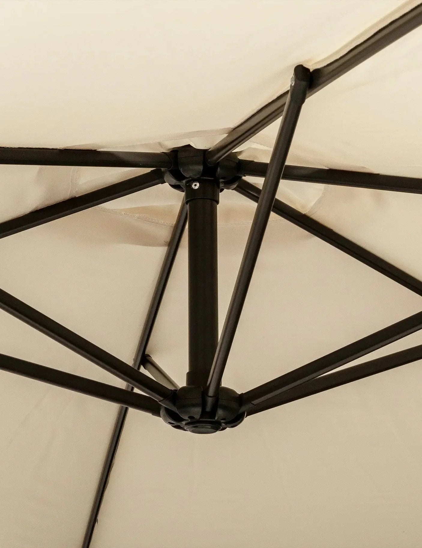 Close-up of beige outdoor parasol canopy with black metal frame and support arms