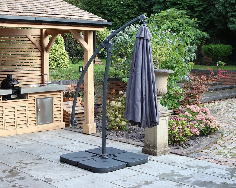 Cantilever garden parasol with grey canopy on patio beside outdoor kitchen and plants
