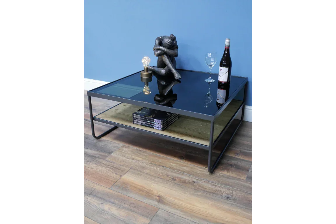 Black glass coffee table with wooden shelf, wine bottle, glass, books and sculpture