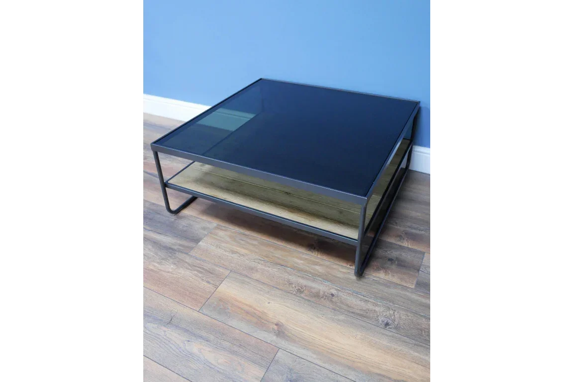 Square glass coffee table with black metal frame and wooden shelf on wood flooring