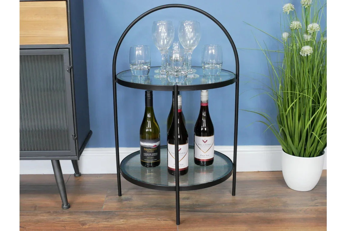 Round metal and glass bar cart with three wine bottles and assorted glassware on shelves
