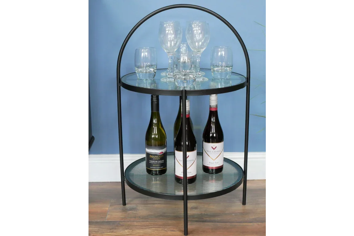 Round glass and metal drinks trolley with wine bottles on lower shelf and glasses on top
