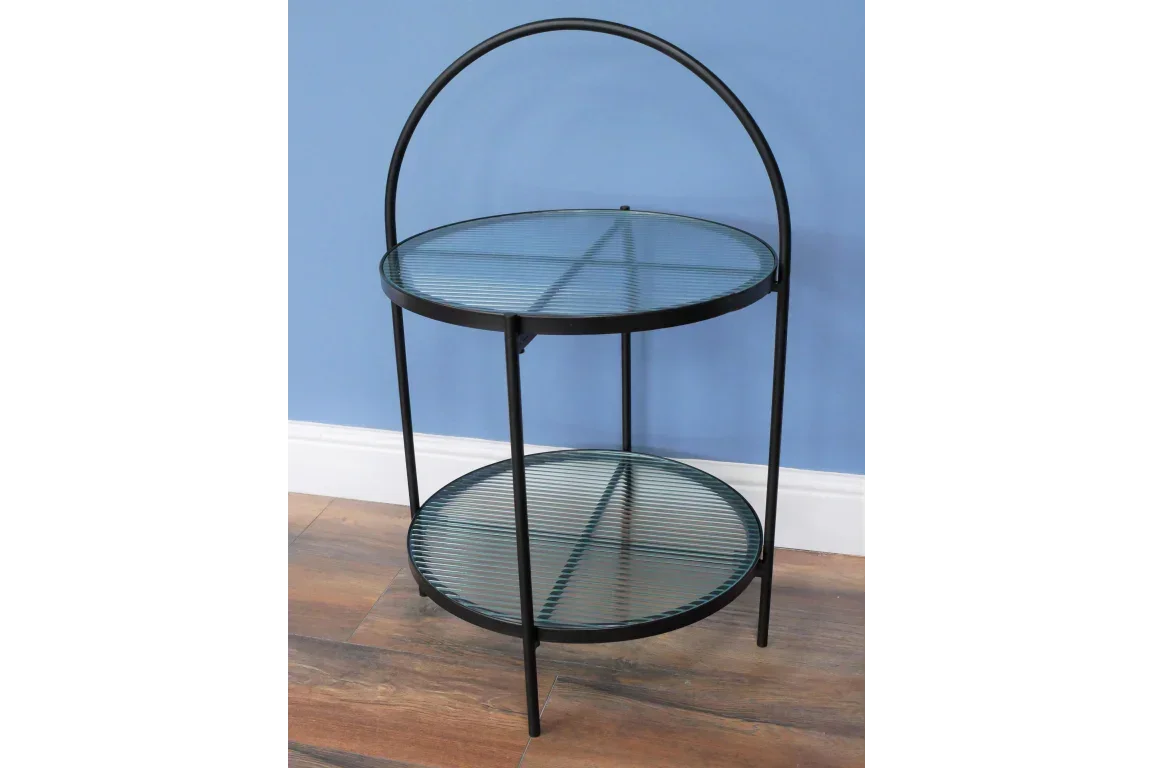 Black metal round side table with two glass shelves against blue wall and wooden floor