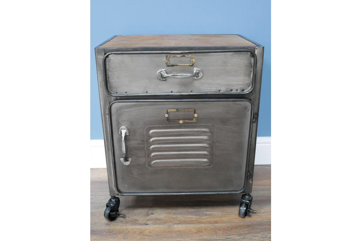 Industrial metal bedside cabinet with drawer, cupboard, and wheels on wood floor