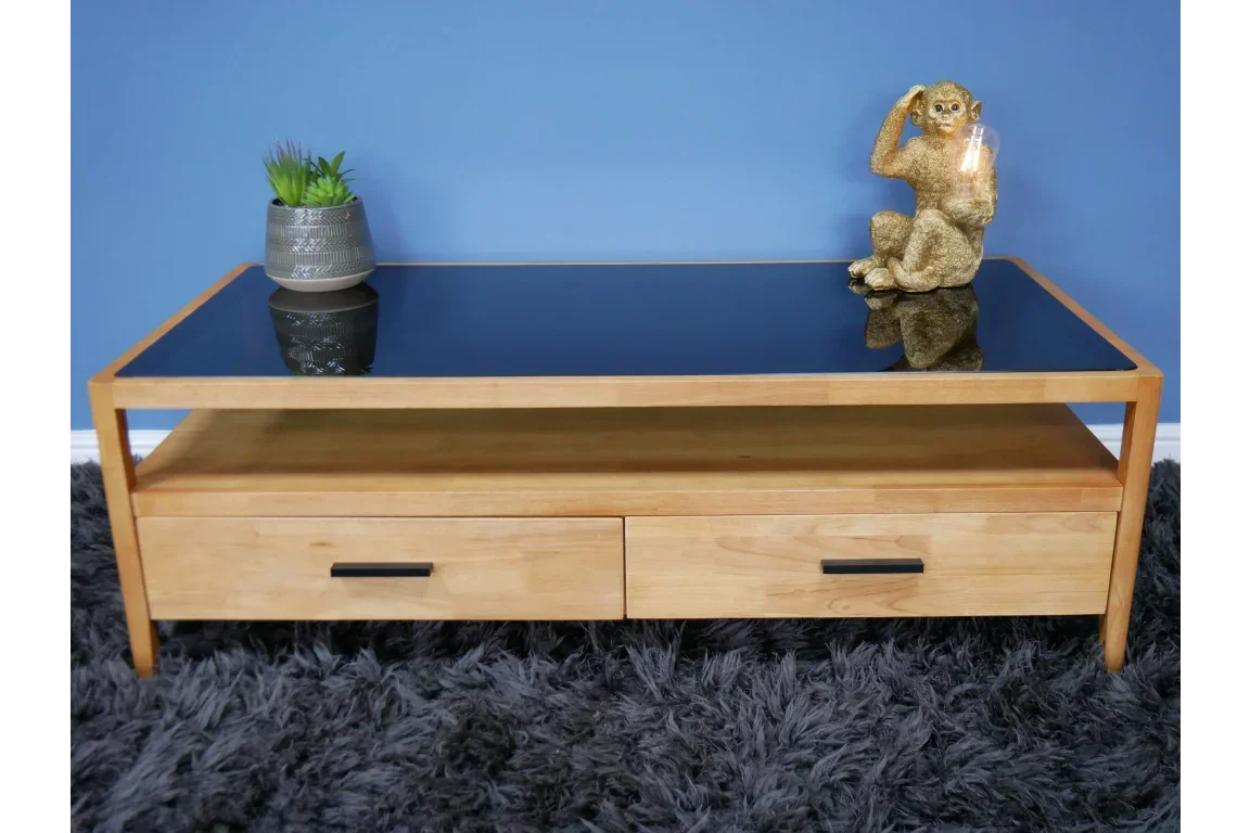 Wood coffee table with black glass top, two drawers, plant and gold monkey lamp decor