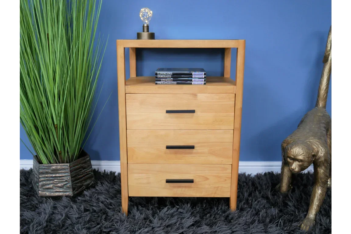 Oak bedside table with three drawers and open shelf, styled with books and lamp