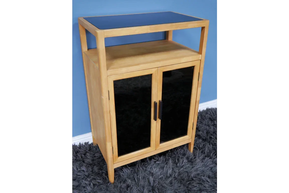 Oak cabinet with black glass doors and shelf, positioned on grey rug against blue wall