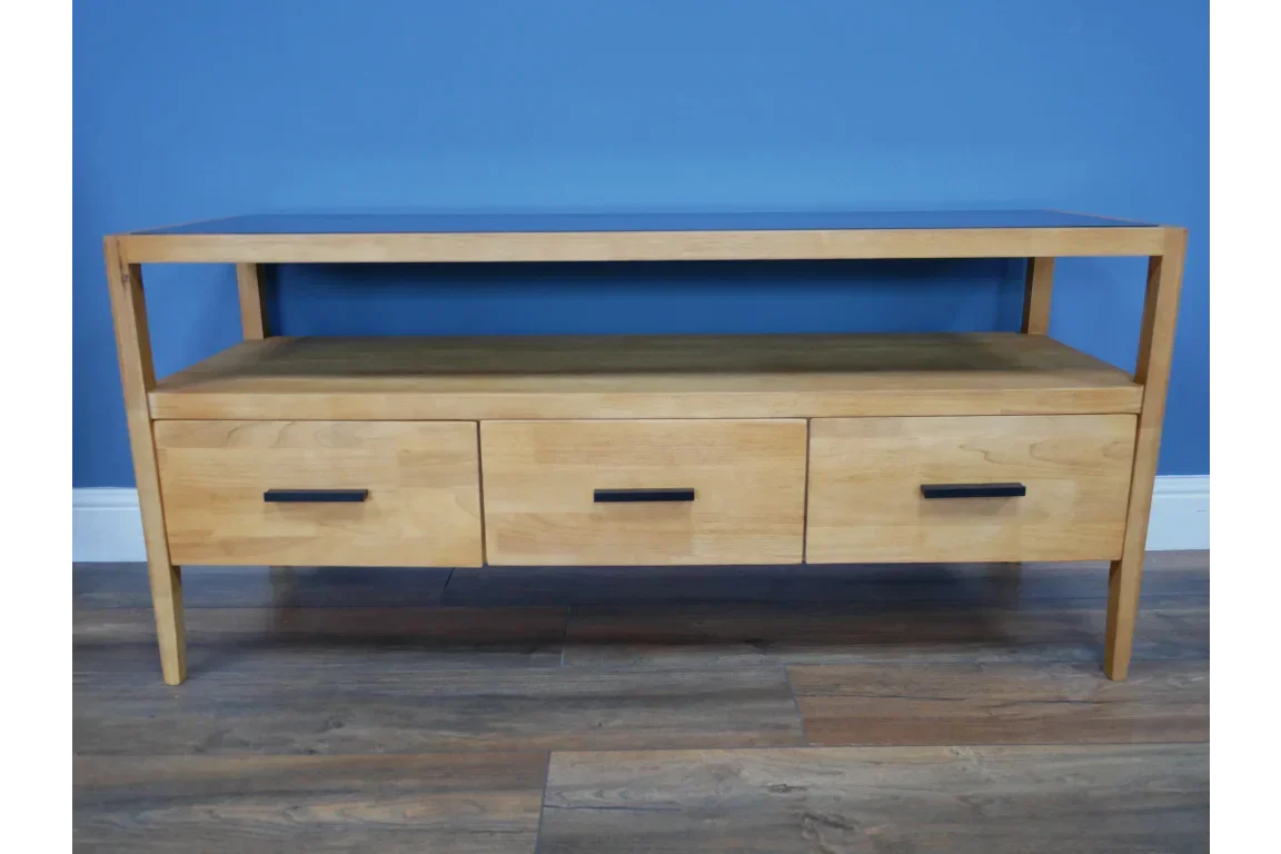 Oak TV unit with three drawers and black handles against blue wall and wooden floor