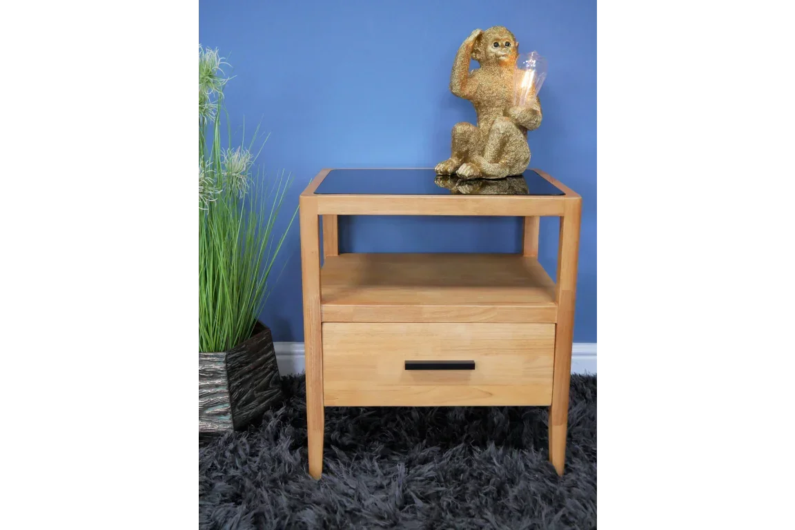 Oak bedside table with black glass top, single drawer, and open shelf on dark rug