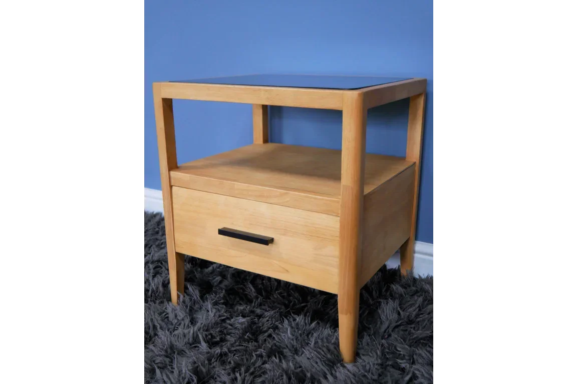 Light oak bedside table with drawer, open shelf and black handle on grey rug