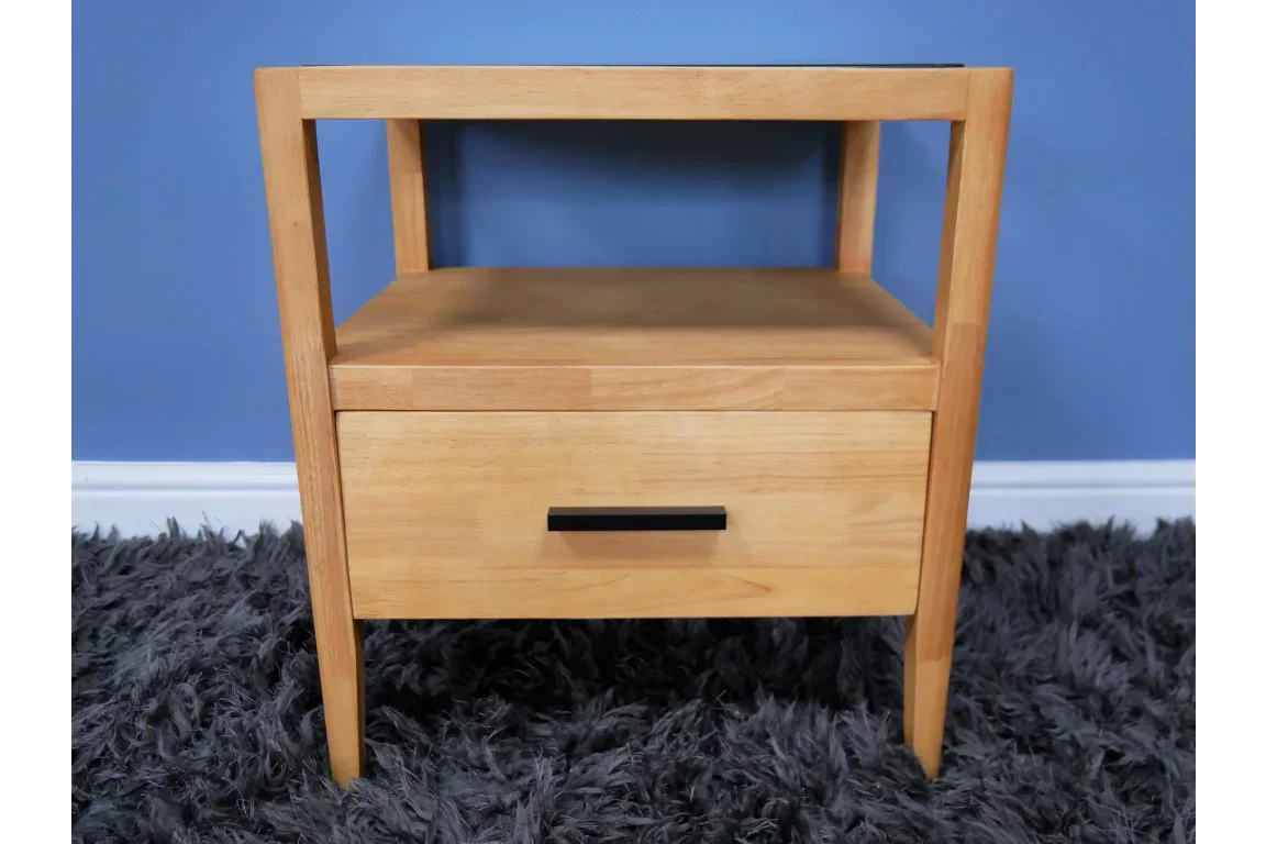 Oak bedside table with open shelf, single drawer and black handle on grey rug