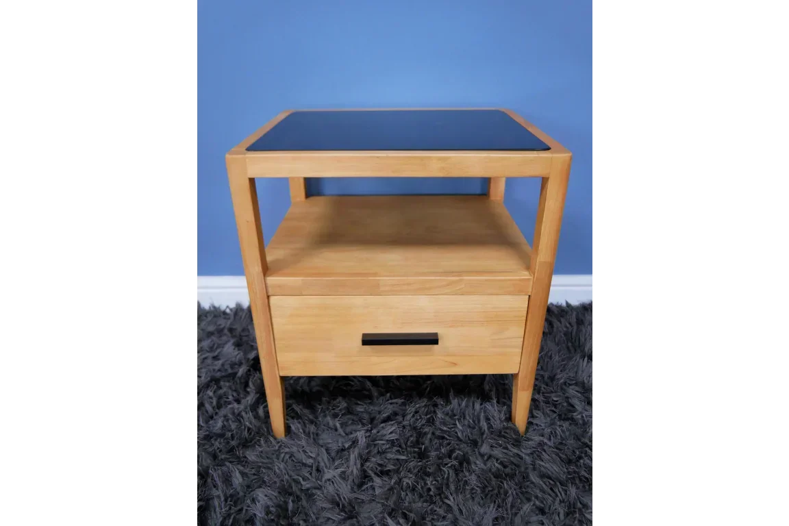 Oak bedside table with black glass top, single drawer and open shelf on grey rug