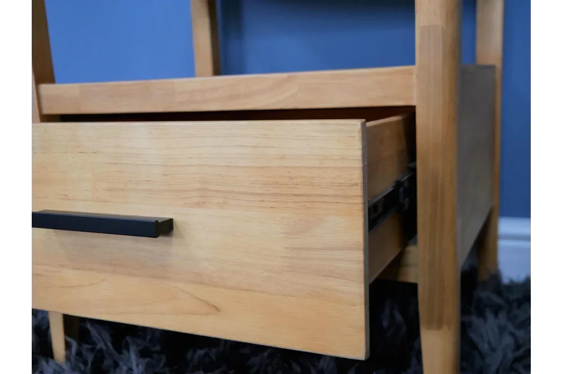 Light wood drawer unit with black metal handle on black carpet