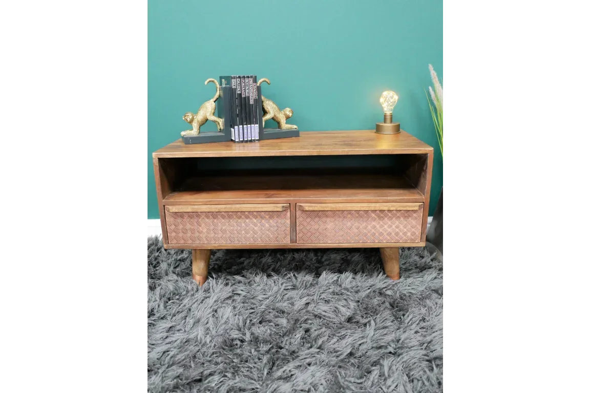 Wooden TV unit with two patterned drawers, open shelf, books and lamp on top, on grey rug