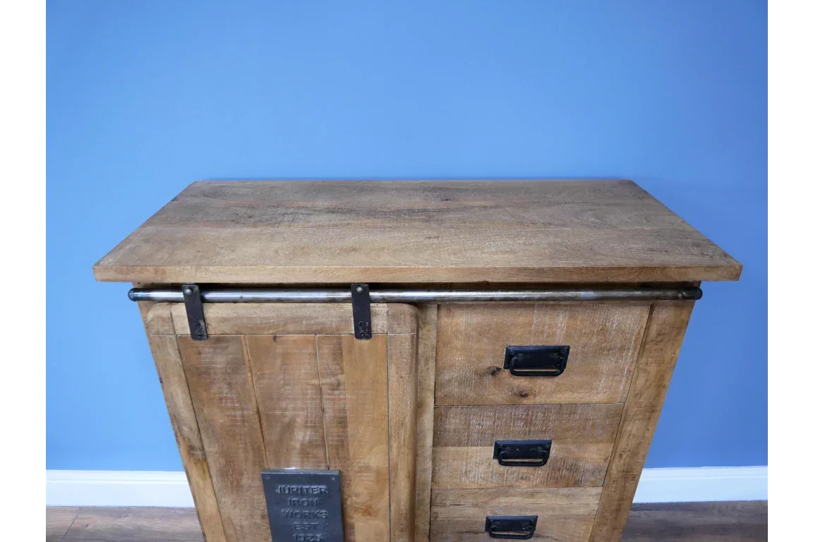 Rustic wood sideboard with sliding barn door and black metal handles against blue wall