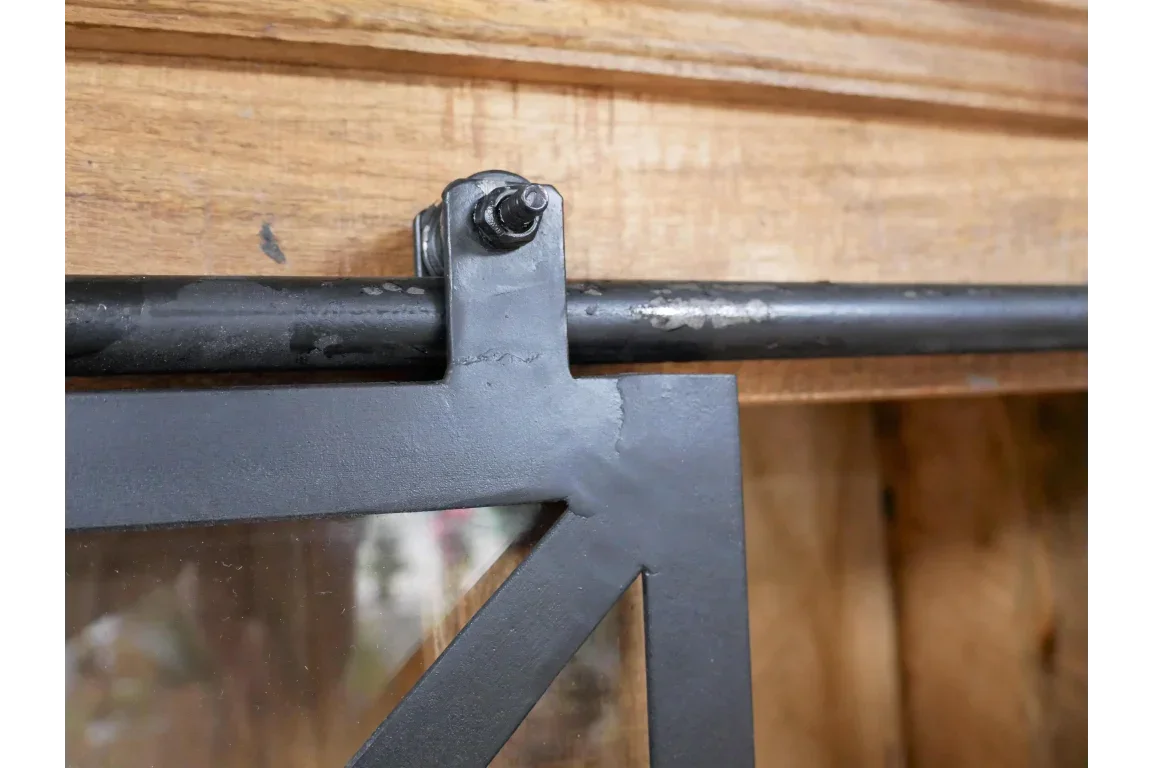 Close-up of black sliding barn door hardware on wood furniture cabinet