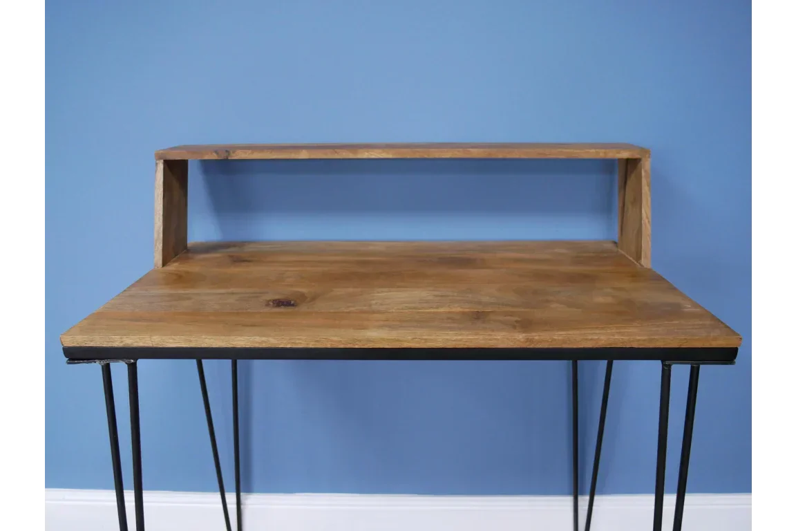 Wood desk with raised shelf and black metal hairpin legs against blue wall