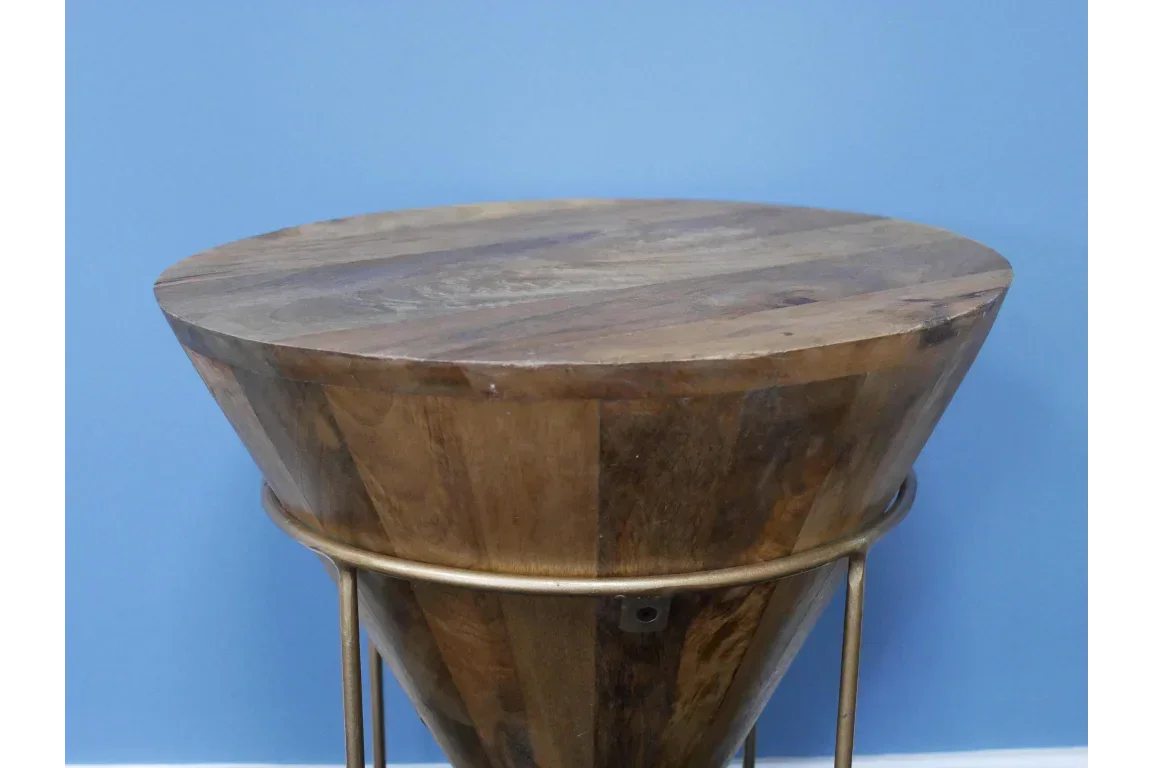 Round wooden side table with natural finish and gold metal legs against blue wall