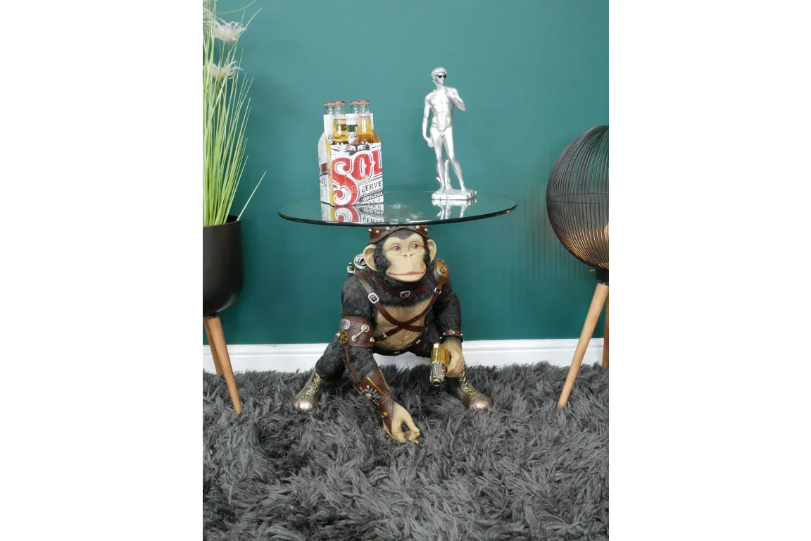 Steampunk monkey side table with round glass top in living room setting on grey rug