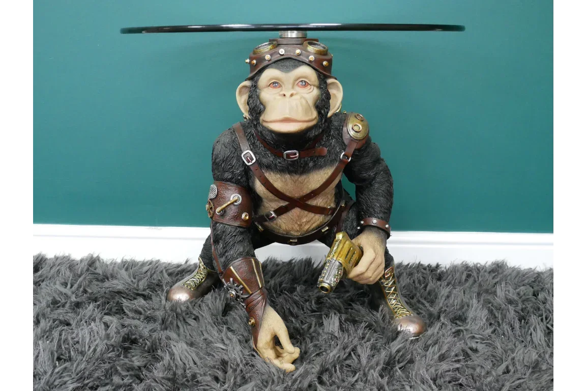 Steampunk monkey side table with glass top and detailed gold and bronze accents on shag rug