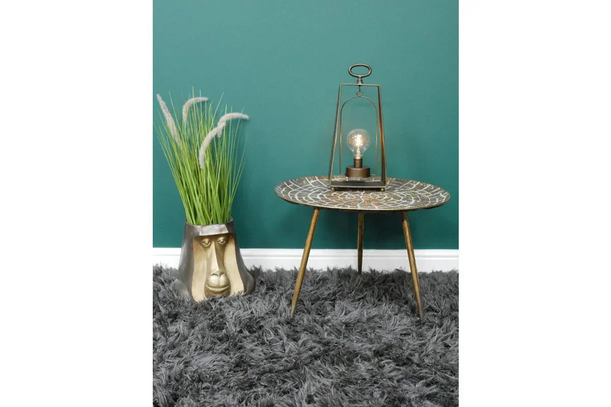 Round side table with patterned top, decorative lamp, and gold monkey-shaped plant pot