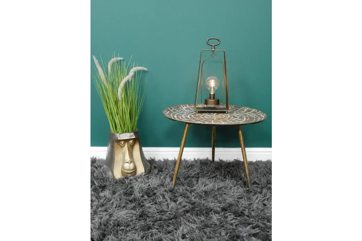 Round metal side table with tripod legs, geometric top, accent lamp and gold face planter
