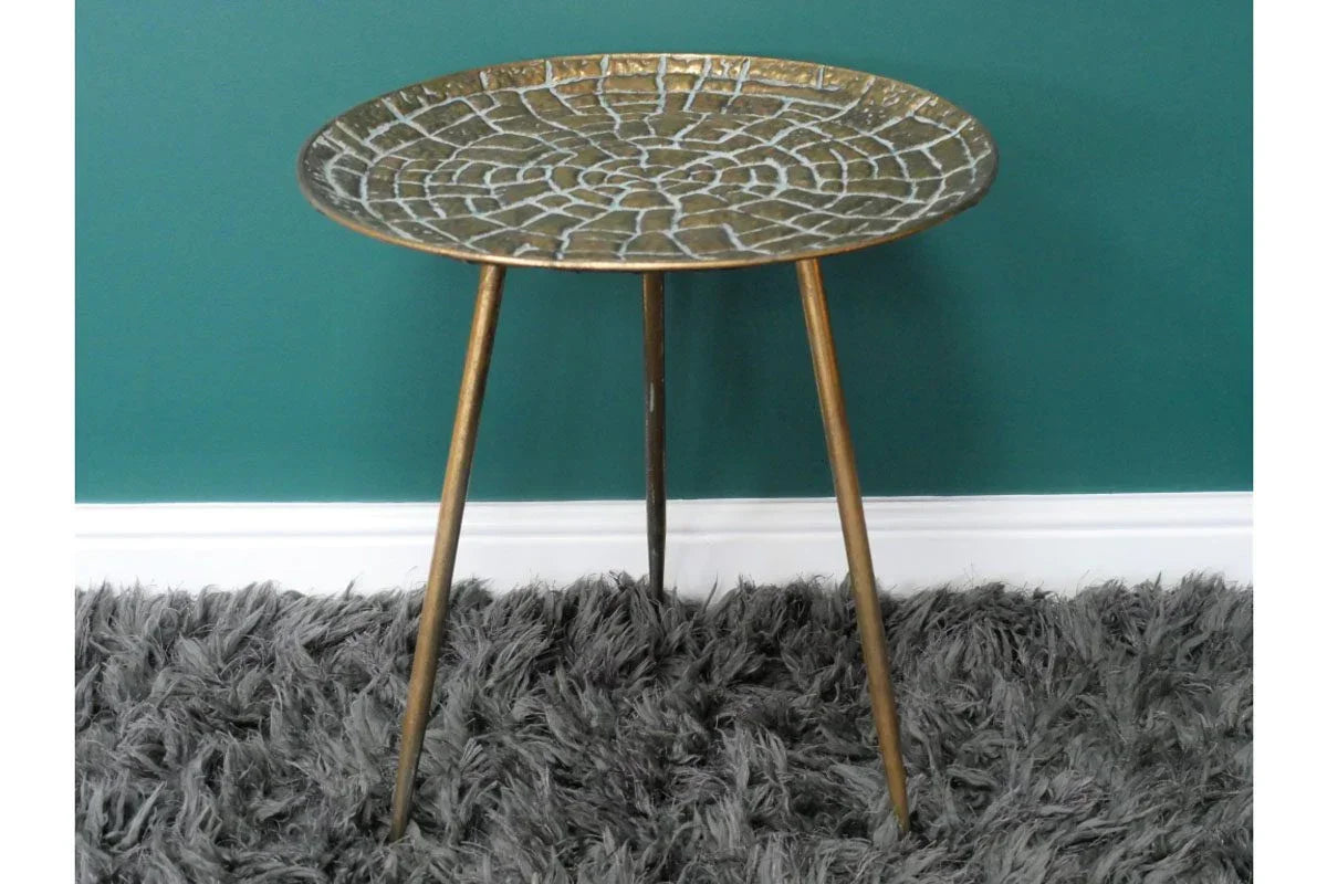 Round metal side table with mosaic top and tripod legs on grey shaggy rug