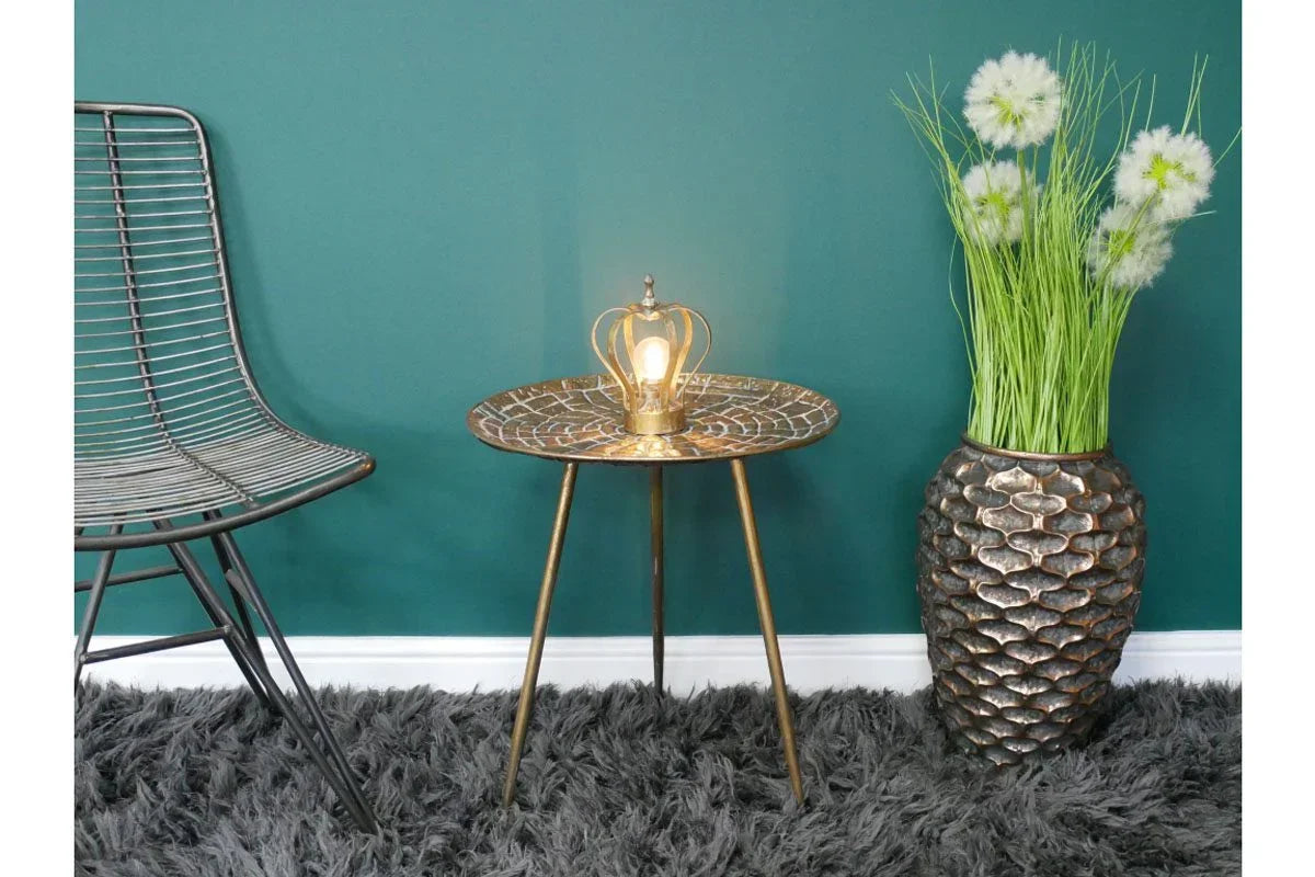 Round gold textured side table with crown lamp, metal chair and vase on grey rug