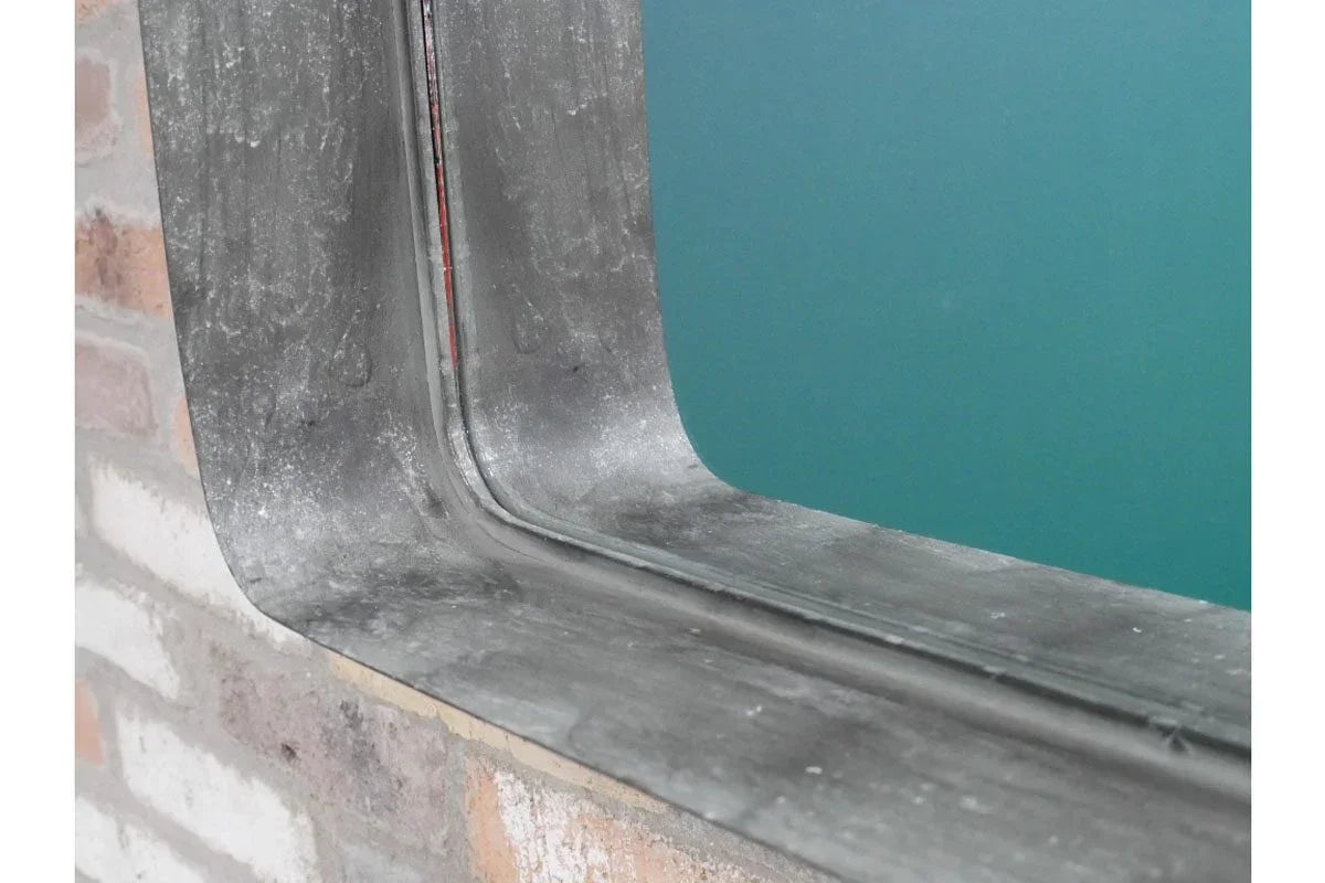 Close-up of industrial metal mirror frame against brick wall