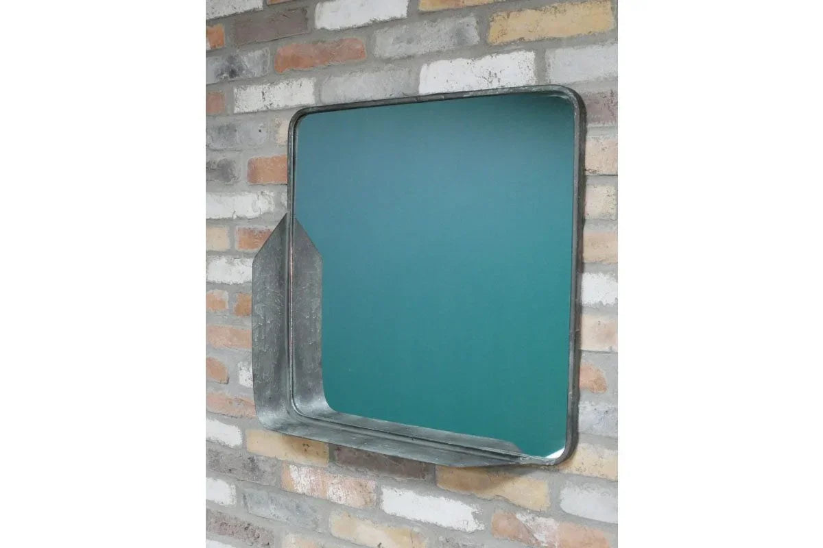 Square metal wall mirror with angled frame on exposed brick wall