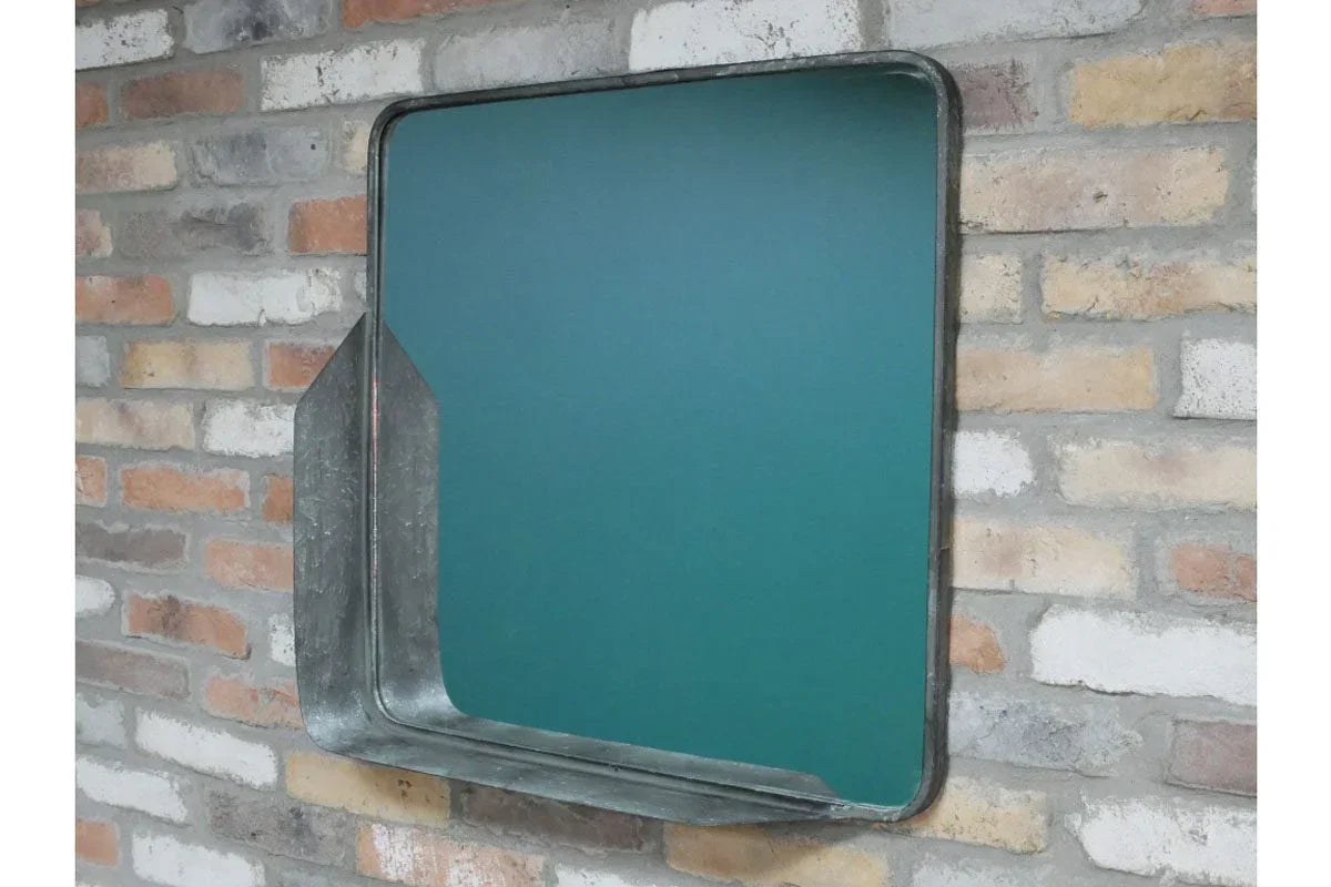 Industrial style metal wall mirror with angled frame on exposed brick wall