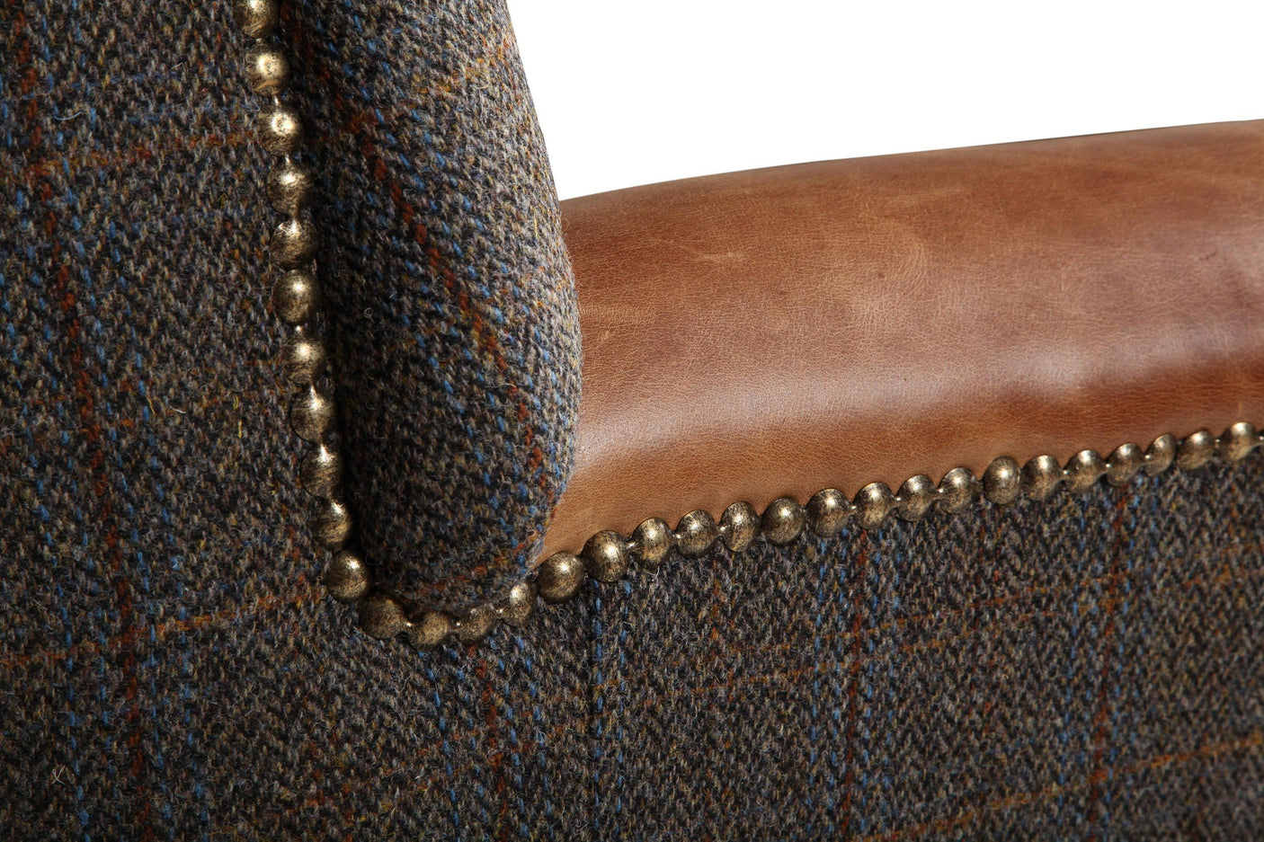 Close-up of tweed armchair with brown leather seat and brass stud detailing