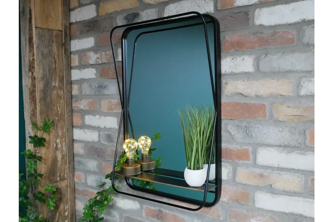 Rectangular black metal wall mirror with shelf holding decorative bulbs and small plant