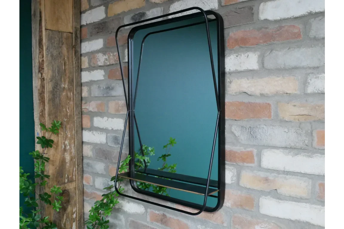 Rectangular wall mirror with black metal frame and integrated shelf on exposed brick wall