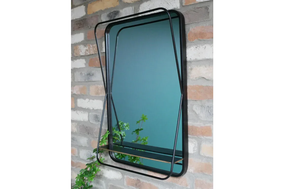 Rectangular wall mirror with black metal frame and shelf on exposed brick wall