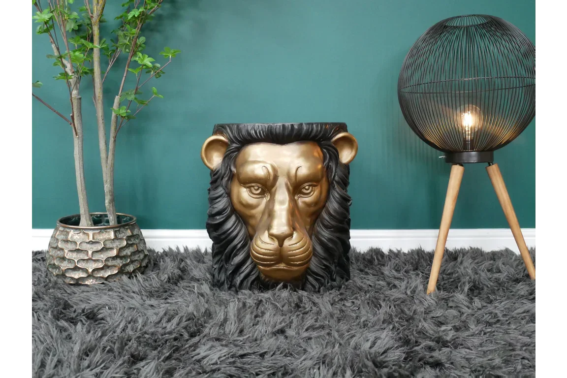 Gold lion head side table on grey rug beside indoor plant and tripod floor lamp