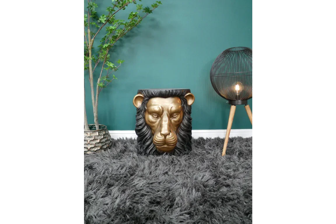 Gold lion head side table on grey rug with green wall, indoor lamp, and plant decor