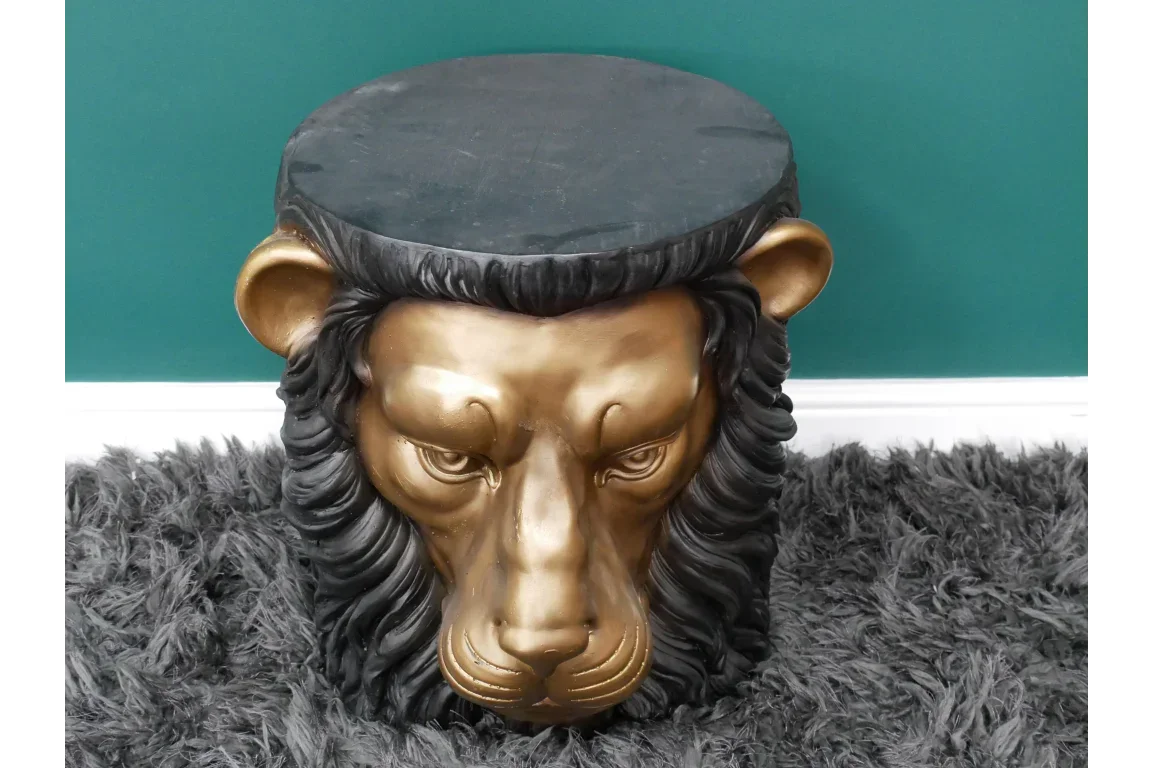 Bronze lion head side table with black top on grey shaggy rug