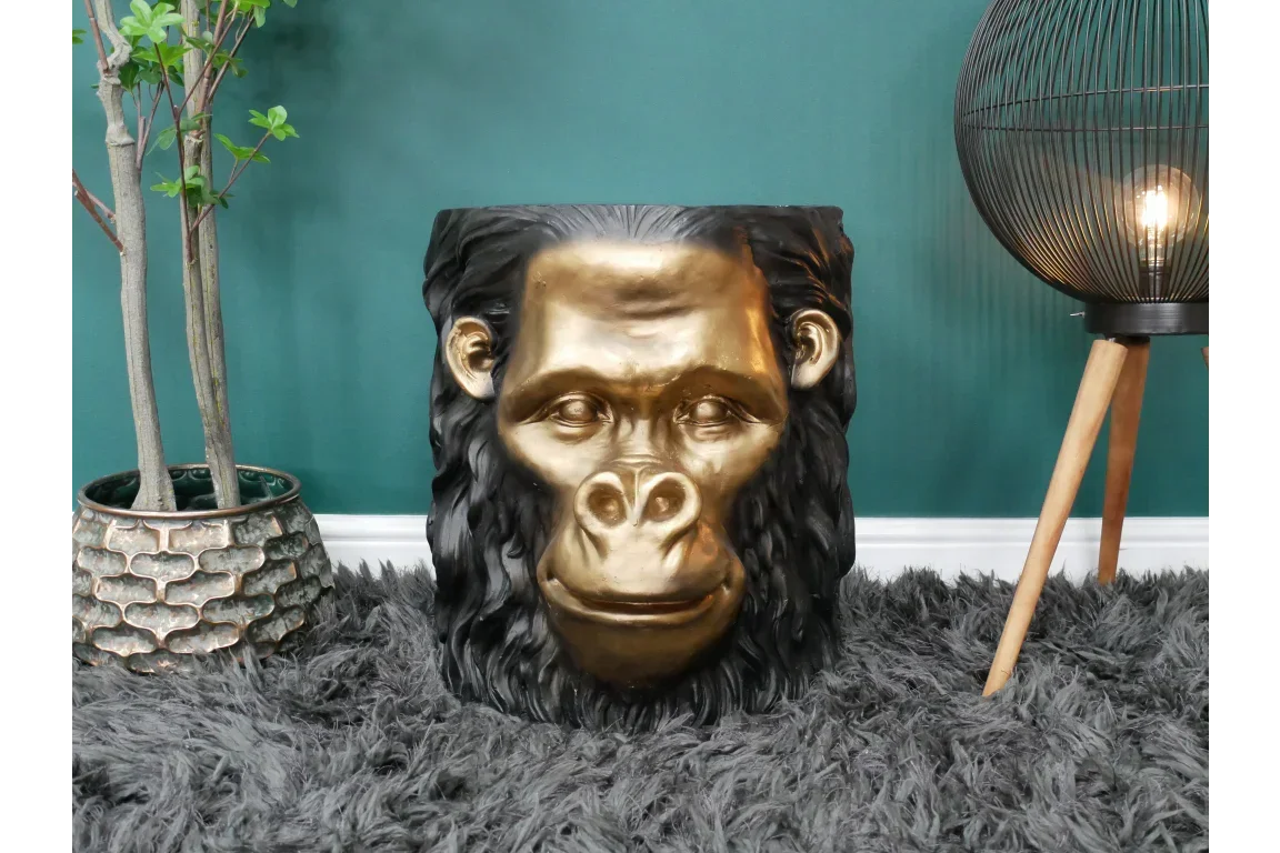 Gold black gorilla head side table on grey rug against a teal wall