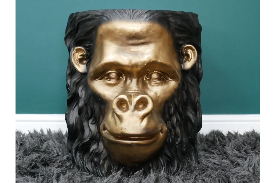 Gold and black gorilla head planter with textured hair on grey rug