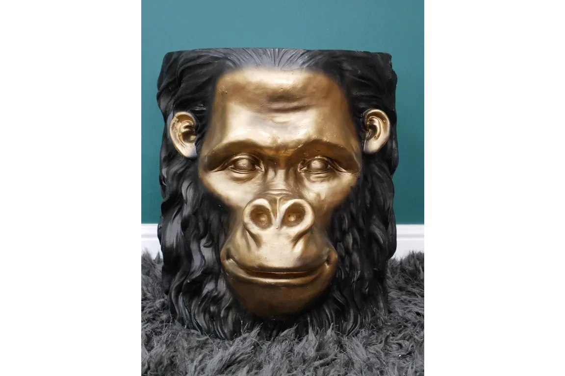 Gold and black monkey face side table with sculpted detailing on grey carpet