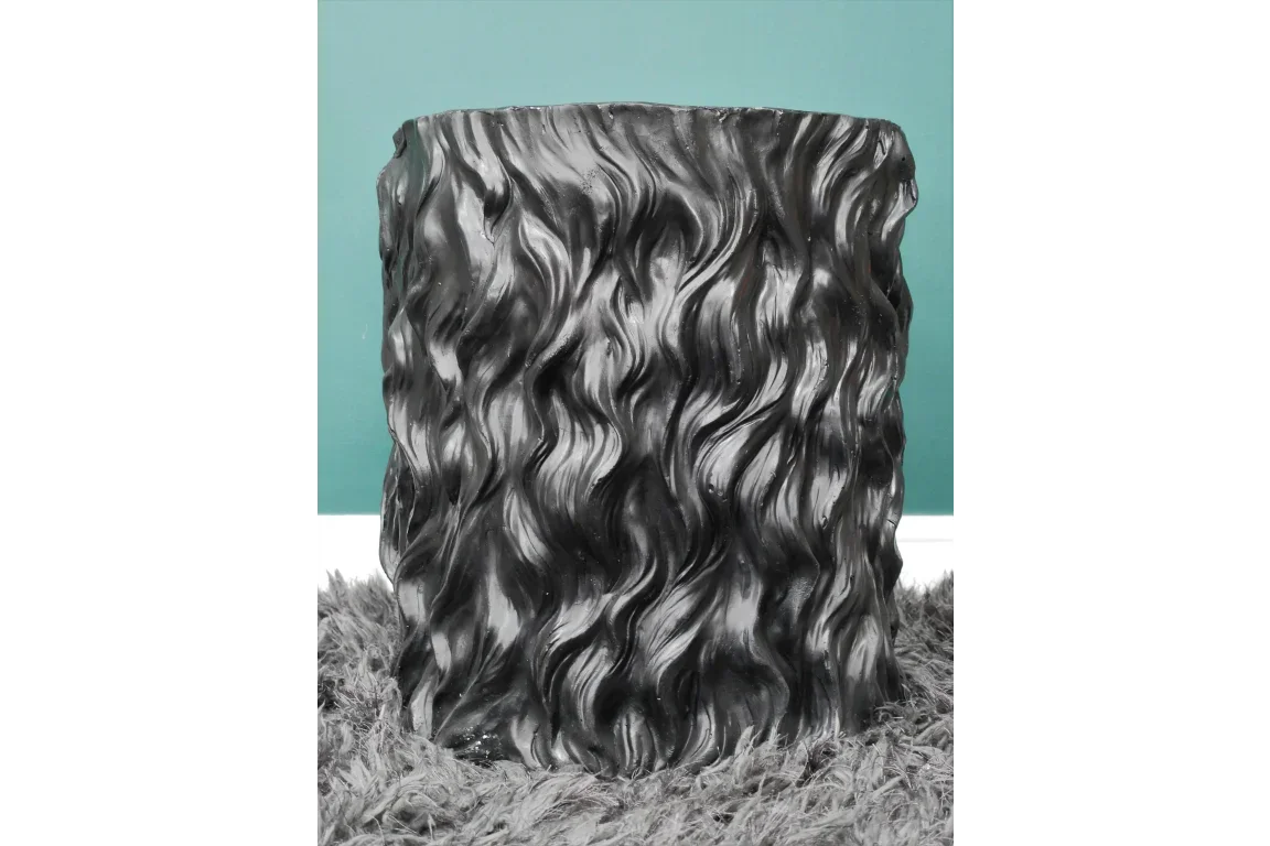 Black textured accent side table with wavy pattern on shaggy grey rug