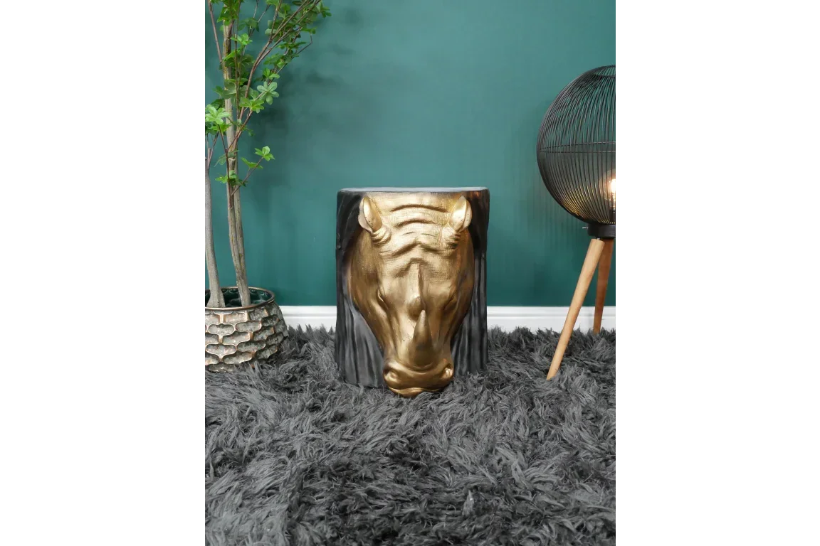 Gold horse head accent table on grey rug beside plant and floor lamp