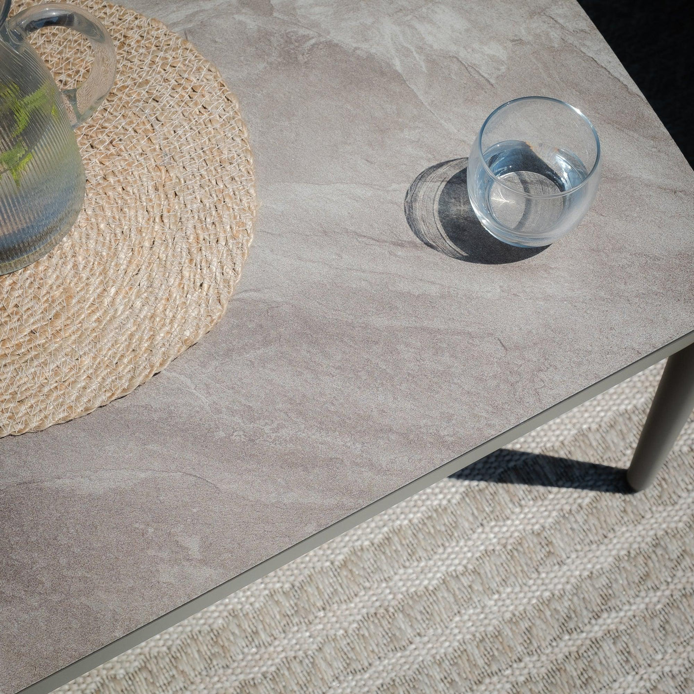 Stone effect dining table top with glass and woven table mat, angled view